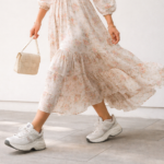 Woman wearing a soft floral midi dress paired with chunky white sneakers, demonstrating the Wrong Shoe Theory styling concept of contrasting feminine outfits with casual footwear.
