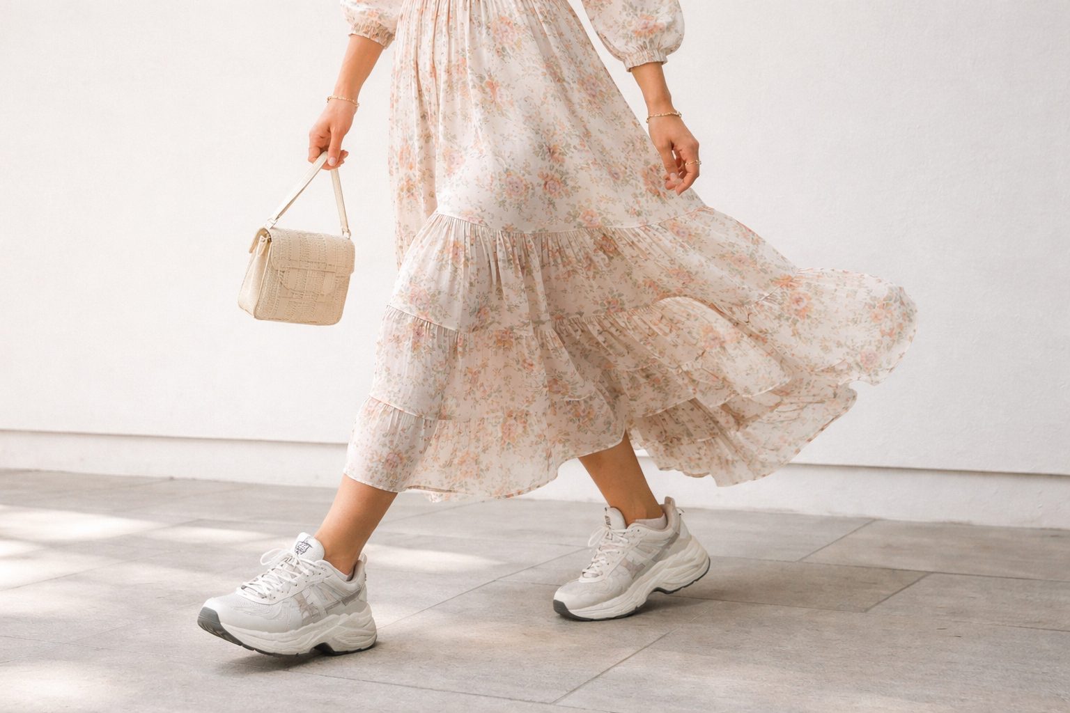 Woman wearing a soft floral midi dress paired with chunky white sneakers, demonstrating the Wrong Shoe Theory styling concept of contrasting feminine outfits with casual footwear.
