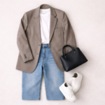 Model off duty style flat lay outfit featuring oversized neutral blazer, white T-shirt, straight-leg jeans, white sneakers and structured handbag on a minimal beige background.