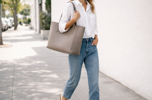 Woman carrying a structured leather tote bag styled with a white button-down shirt, straight-leg jeans and loafers in an effortless everyday outfit.