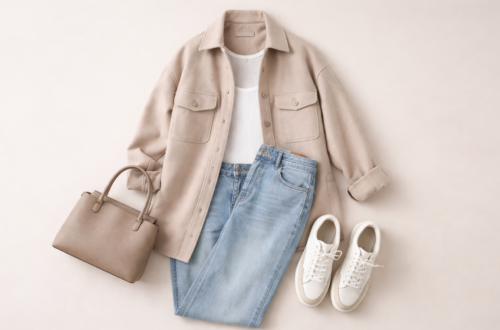 Neutral shacket outfit flat lay featuring a beige oversized shirt jacket, white ribbed tank, straight-leg jeans, white sneakers and taupe handbag on a minimalist background.
